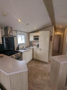 a kitchen with white cabinets and a white refrigerator at Hidden Gem Wilksworth Caravan Park Rural and Peaceful Setting in Wimborne Minster