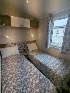 two beds in a small room with a window at Hidden Gem Wilksworth Caravan Park Rural and Peaceful Setting in Wimborne Minster