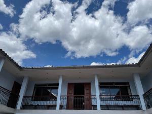a white house with a blue sky and clouds at Hotel Restaurante Minas Cocha in Chavín de Huantar