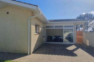 une maison avec une porte coulissante en verre et une terrasse dans l'établissement Maison proche de la plage - 0971, à Vendays-Montalivet