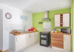 a kitchen with white cabinets and green walls at Nanhoron House in Nefyn