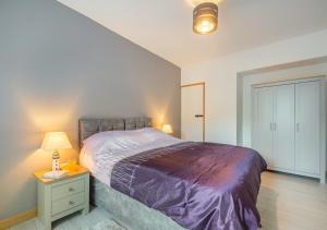 a bedroom with a bed and a table with a lamp at Nanhoron House in Nefyn