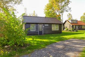 una pequeña casa negra con un patio de césped en Vakantiepark de Eikenhof, en Paasloo