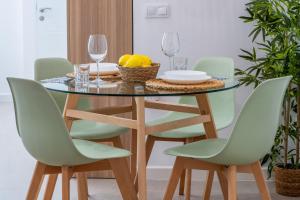 a dining room table with green chairs and a table with wine glasses at Apartamentos Alnatur in Córdoba