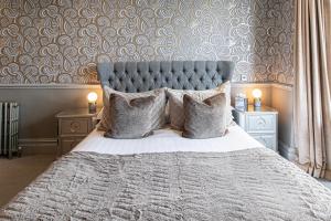 a bedroom with a bed with a gray headboard and pillows at Escape Boutique B&B in Llandudno