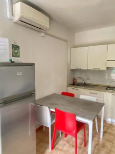 cocina con mesa con sillas rojas y nevera en Grazioso Appartamento n 40 a Bibione a 100mt dal mare, en Bibione