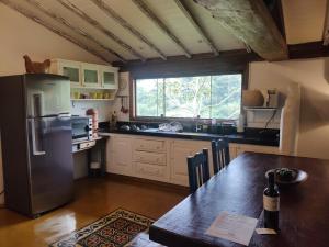 a kitchen with a stainless steel refrigerator and a table at Casa Moitará in Tiradentes