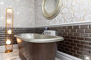 a metal tub in a bathroom with a mirror at Escape Boutique B&B in Llandudno