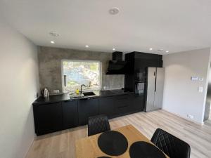 uma cozinha com armários pretos, uma mesa e uma janela em Eksluzywny apartament w zaciszu em Kristiansund