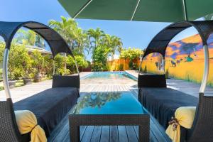 a swimming pool with two chairs and an umbrella at Maison d'invités dans jardin tropical avec piscine à Tahiti in Atiue