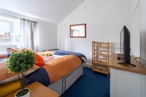 a bedroom with a bed and a television and a desk at Cosmopolitan Comforts Flat in Coventry