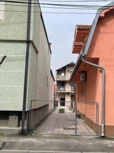 an alleyway between two buildings with a fence at Apartmani Dora Leskovac in Leskovac