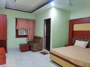 een slaapkamer met een bed en een stoel bij OYO Hotel Anandam Residency in Dhanbad