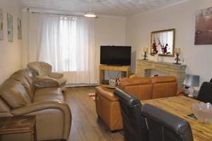 a living room with leather furniture and a television at Aderyn Mawr Cottage in Blaina