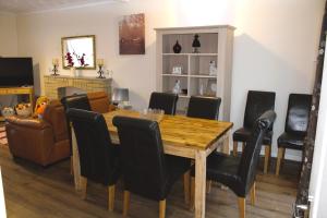 een eetkamer met een houten tafel en zwarte stoelen bij Aderyn Mawr Cottage in Blaina