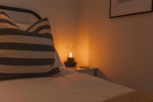 - un lit avec un oreiller et une bougie sur une table dans l'établissement Bridge Apartment, à Stockport