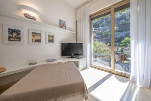 een slaapkamer met een bed, een tv en een raam bij CASA ISABELLA Relax con Piscina in Rapallo