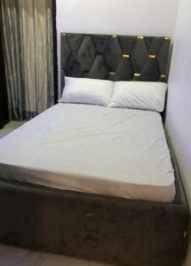 a bed with a black headboard and white sheets and pillows at Beautiful 3-Bed House in Lekki in Ikota