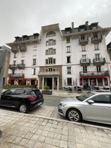 dos coches estacionados frente a un gran edificio en Chambre centre Saint-Gervais Mont-Blanc en Saint-Gervais-les-Bains