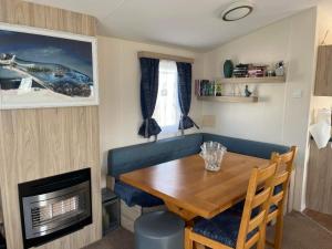 a small dining room with a wooden table and a fireplace at Lyntons 3 bedroom caravan pets stay free in Heacham