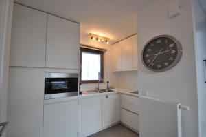 a kitchen with white cabinets and a clock on the wall at De witte oase 22 in Oostduinkerke