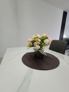 a vase filled with pink flowers on a table at Cozy Nest at Coutryhomes Rawang by Bliss Stay Management in Rawang