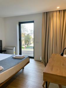 1 dormitorio con cama, mesa y ventana en Hotel Quinta da Tulha, en Guimarães