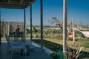 a porch with a table and chairs and a view of a field at NEW Exclusive Lodges, Marzamemi, Noto in Pachino