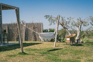 a hammock in a yard with a chair and a fence at NEW Exclusive Lodges, Marzamemi, Noto in Pachino