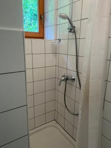 a shower with a hose in a white tiled bathroom at Hostel Črjanski raj in Črna na Koroškem