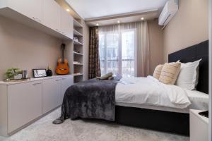 Schlafzimmer mit einem Bett mit Gitarre in der Unterkunft Modern & Elegant City Center Apartments in Plowdiw