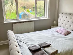 a bed with two towels on it in front of a window at Rooms at EEJ homes in London