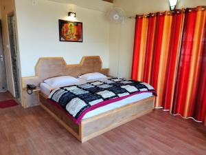 a bedroom with a bed with red and orange curtains at Elphinstone Inn in Almora