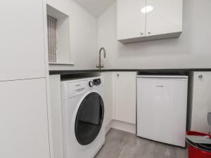 uma cozinha branca com uma máquina de lavar roupa e um lavatório em The Lodge House em Lancaster