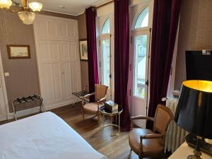 a bedroom with a bed and chairs and a window at Le Castel Guesthouse in Bayeux