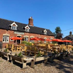 a restaurant with wooden tables and chairs and umbrellas at The Half Moon Inn Rushall IP21 4QD in Pulham Saint Mary the Virgin