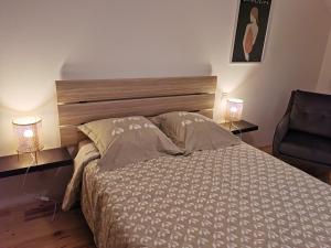 um quarto com uma cama com 2 candeeiros e uma cadeira em Appartement à Valognes : Entre Terre et Mer em Valognes