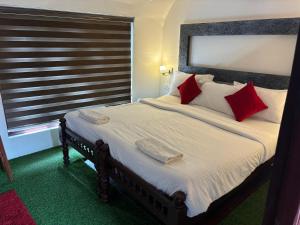 a bedroom with a large bed with red pillows at PUNNAMADAKKARAN CRUISE in Alleppey