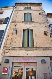 een hoog bakstenen gebouw met een bord erop bij La Taverne in Uzès