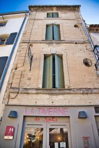 un alto edificio di mattoni con un cartello sopra di La Taverne a Uzès