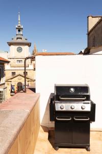 a grill on a rooftop with a clock tower at Green Hostel Oviedo in Oviedo