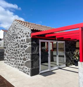 a stone building with a red roof and a door at Aires Hostel in São Roque do Pico