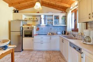 eine Küche mit weißen Schränken und einem Kühlschrank in der Unterkunft Villa Emmanuela in (( Klonátika ))