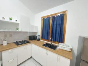 uma cozinha com armários brancos, um lavatório e uma janela em Sueño caribeño em La Laguna