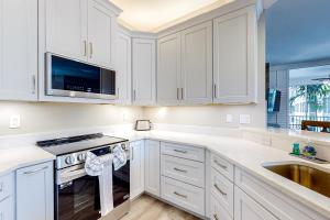 a white kitchen with white cabinets and a sink at Luxury Condo in Regatta in Naples