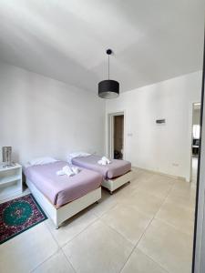 two beds in a room with white walls at Sunshine Court Apartment No 1 in Sliema
