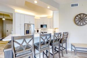 a kitchen with a bar with chairs and a clock at Luxury Condo in Regatta in Naples