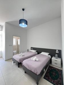 a bedroom with two beds and a light fixture at Sunshine Court Apartment No 1 in Sliema