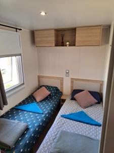 two beds in a small room with blue pillows at Mobil-home camping Mar Estang in Canet-en-Roussillon