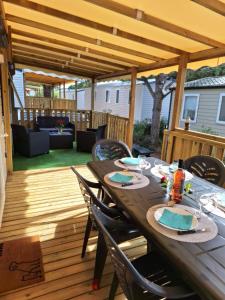 a wooden patio with a table and chairs on a deck at Mobil-home camping Mar Estang in Canet-en-Roussillon